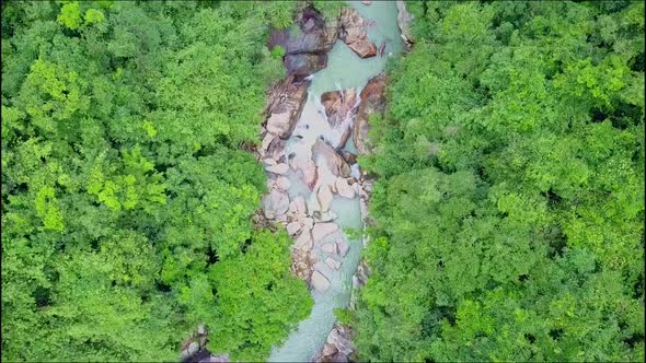 Flycam Moves High Above Narrow River in Tropical Rainforest