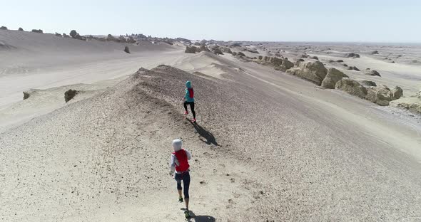 Two women trail runners cross country running in the desert, slow motion