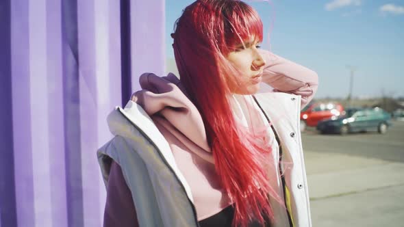 Portrait of Independent Young Woman with Pink Hair Posing on Purple Containers Background