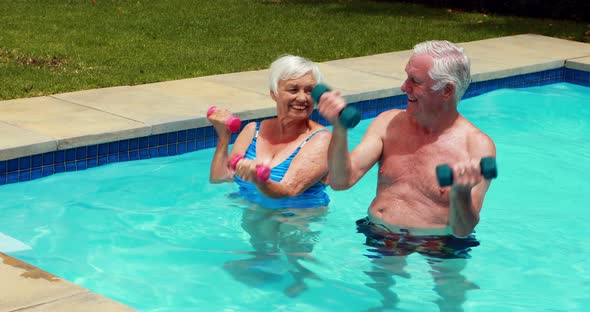 Senior couple exercising with dumbbells in the pool