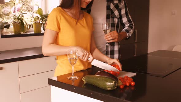 Woman chopping vegetable while man having champagne