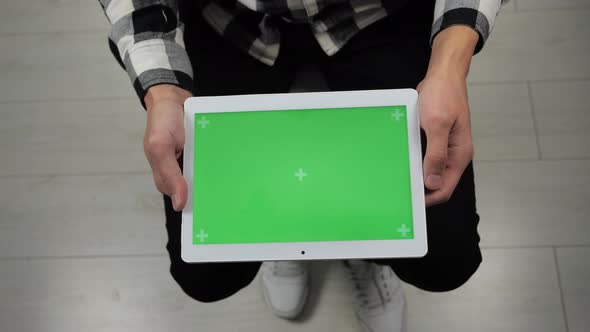 Man Sitting on Chair Looking at Digital Tablet with Green Screen Chroma Key