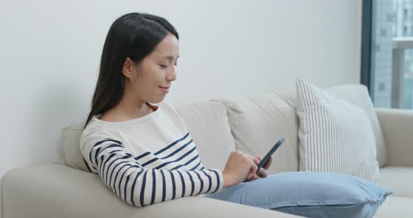 Woman look at mobile phone and sit on sofa