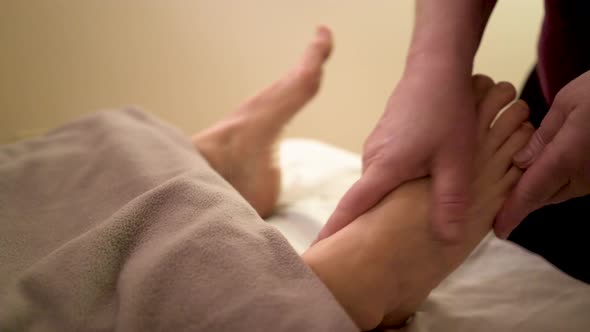 Using a type of ointment a massage therapist works on loosening up the muscles and tendons in a matu