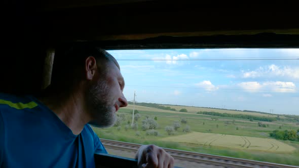 A Man Looks Out the Window of a Train During His Journey