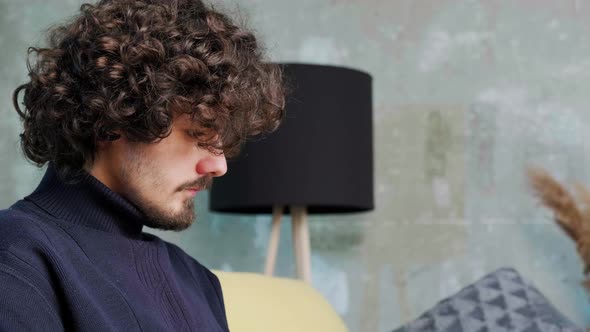 Close Up of an Young Man with Curly Hair That is Browsing at His Laptop