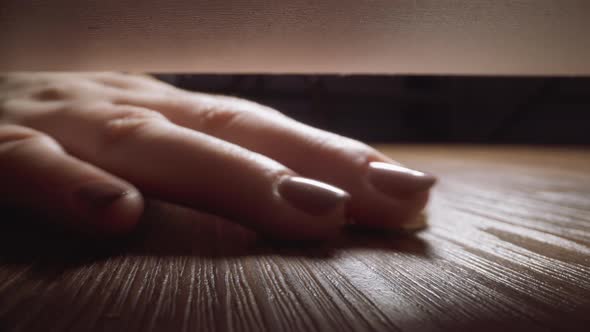 Woman Takes Gold Ring Rolled Under Sofa on Wooden Floor