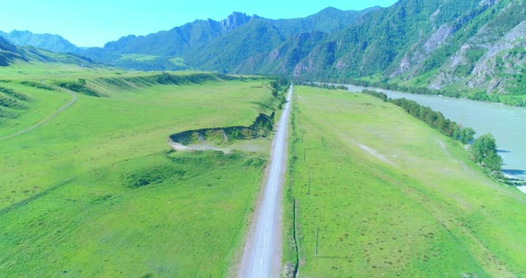 Aerial Rural Mountain Road and Meadow at Sunny Summer Morning. Asphalt Highway and River.