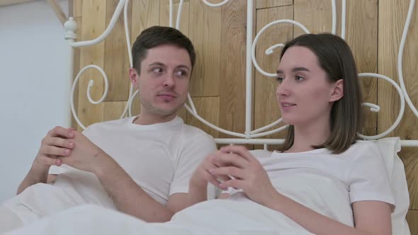 Attractive Young Couple Sitting in Bed and Talking