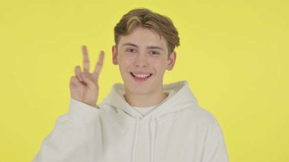Young Man Showing Victory Sign on Yellow Background