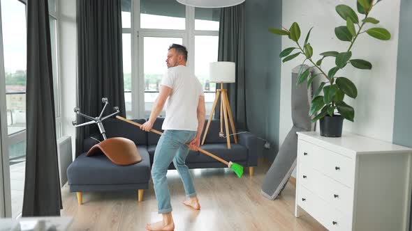 Man Cleaning the House and Having Fun Dancing with a Broom