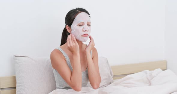 Woman apply paper mask on bed