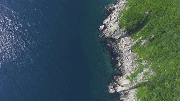 Drone View Above the Sea Along the Rocky Coast and High Cliffs on a Sunny Day.
