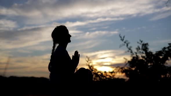 Silhouette of a woman praying with Amazing dramatic sky sunset background.