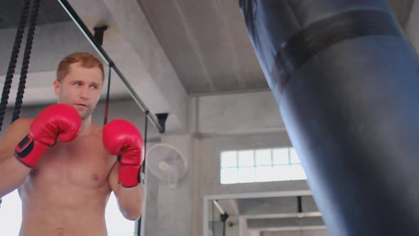 One muscular sport man punch to sandbag and practice in gym for exercise