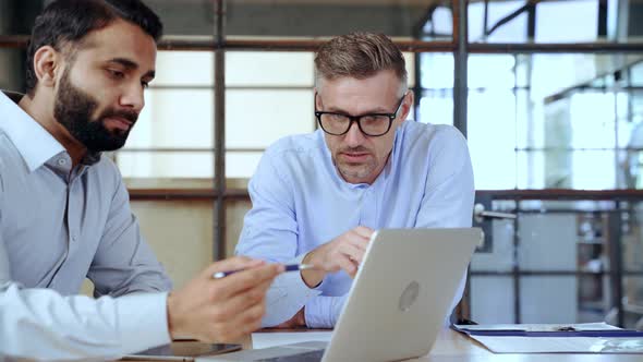 Two Diverse Business Men Discussing Market Data Using Laptop and Digital Tablet