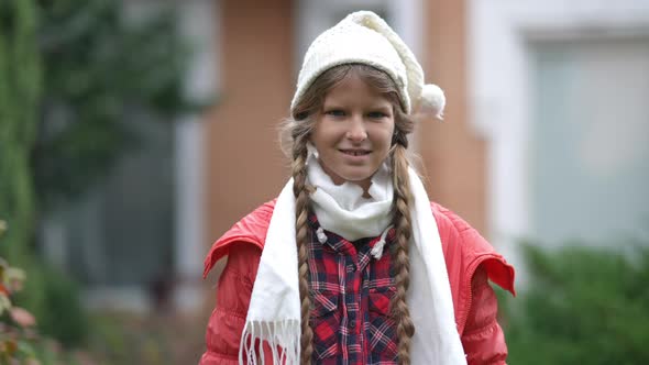 Front View Portrait Smiling Teenage Caucasian Girl in White Hat and Scarf Posing Outdoors on Autumn