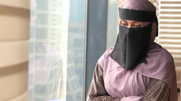 Young Muslim Women Covering Face Looking Through Window Indoor