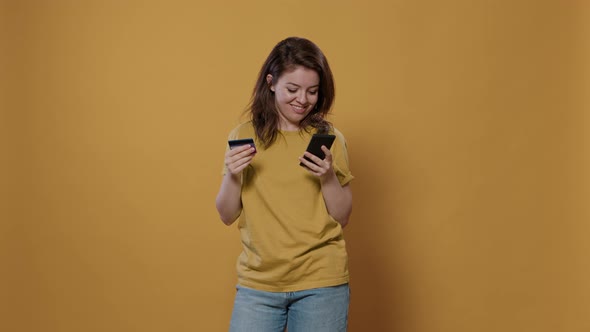 Portrait of Woman Excited About Online Shopping Holding Smartphone Typing Credit Card Details