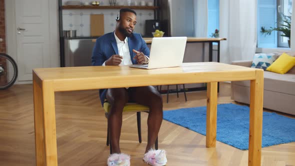 African Businessman Having Video Call on Laptop Working in Underwear at Home Office