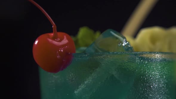 Close Up View on the Edge of a Glass of Green Cocktail Drink with a Red Cherry.