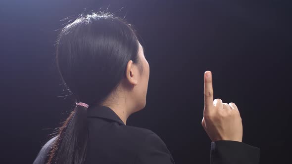 Side View Of Asian Speaker Woman In Business Suit Showing Index Fingers Up While Speaking