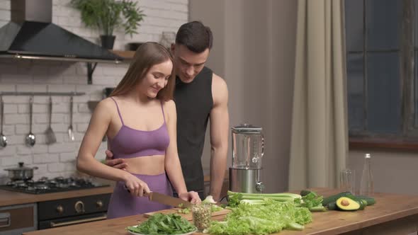muscular young couple cooking healthy cocktail after workout, talking and laughing in the kitchen. 