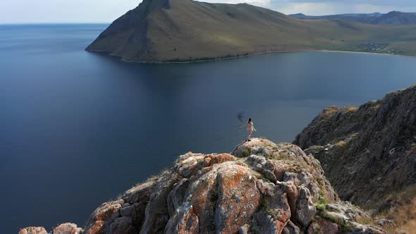 Young Woman in White Short Dress Running Up on Top of Mountain Above the Sea