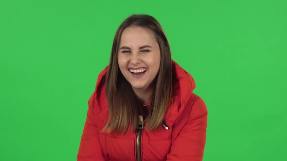 Portrait of Lovely Girl in a Red Down Jacket Is Laughing. Green Screen