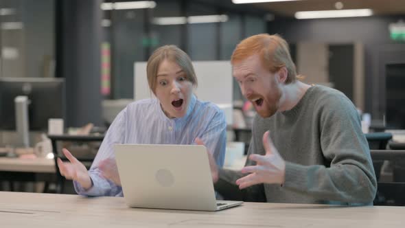 Young Man and Woman Celebrating Success on Laptop