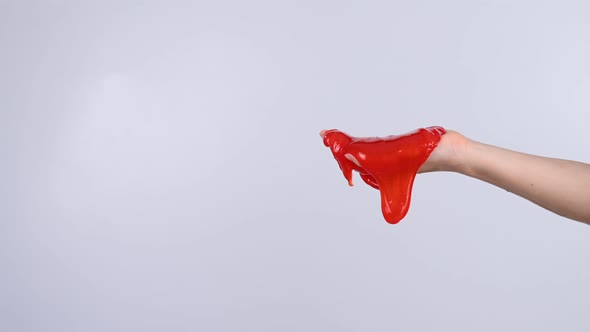 Red Slime Flowing Down From a Woman's Hand on a White Background alt