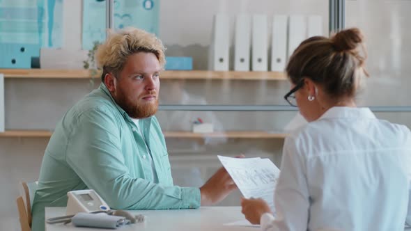 Overweight Man Speaking with Female Doctor in Clinic