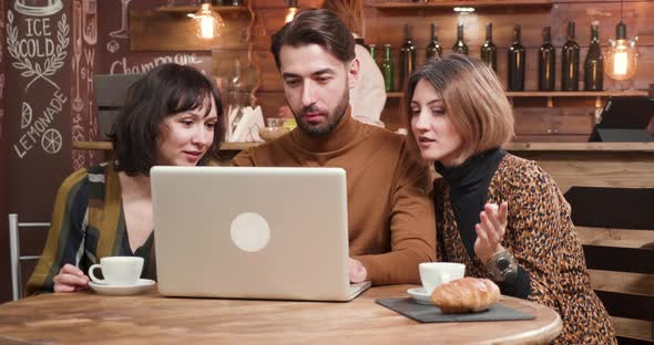 Young Designer Presenting a Project To His Female Colleagues During a Coffee Break