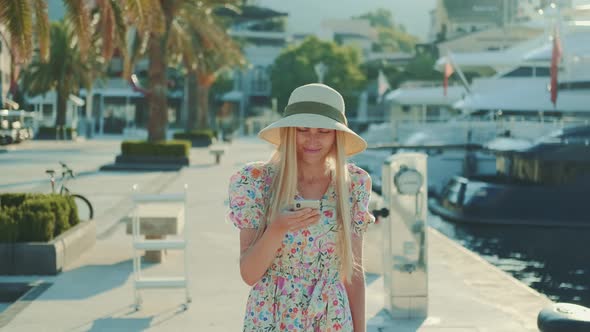 Beautiful Lady in Sun Hat Watching on Smartphone Something and Smiling