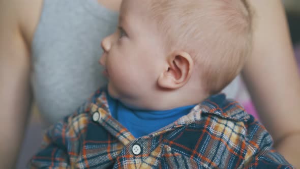 Baby Plays with Glass Dropper Sitting with Mother in Room