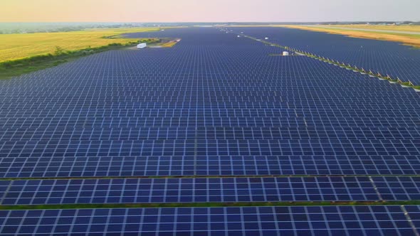Aerial Drone View Into Large Solar Panels at a Solar Farm at Bright Sunset