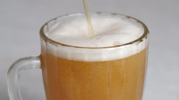 Close-up of beer with a lot of foam being poured into a large bar mug. drinking beer concept. beer b