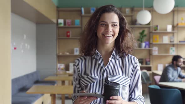 Happy Latin Girl Student Holding Coffee Walking in Campus Hallway