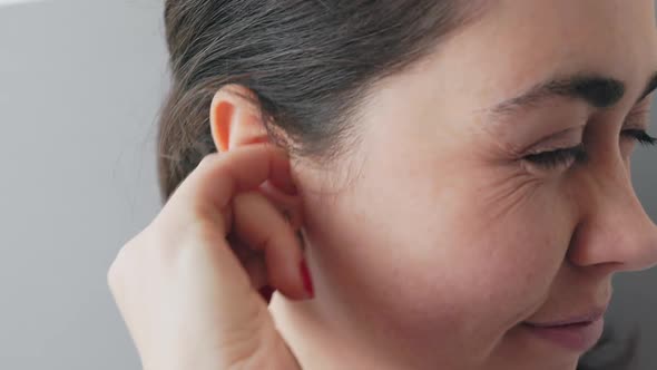 Woman scratching her ear with an earring and piercing inside with her finger