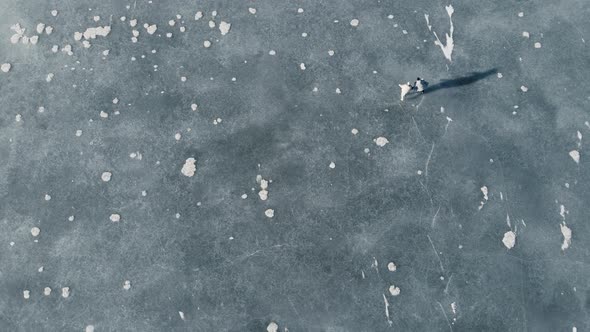 High Aerial Shot of Couple Skating on a Frozen Lake in Beautiful Sunny Landscape
