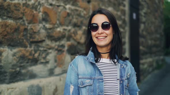 Slow Motion Portrait of Attractive Lady in Trendy Sunglasses and Stylish Clothing Standing Outdoors