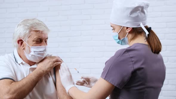 Female Nurse in Uniform Giving Vaccine for Patient in Protective Mask