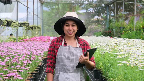 Happy Asian woman caring for plants prepared for sale.