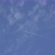 An airplane flies across a blue sky with white clouds. - VideoHive Item for Sale