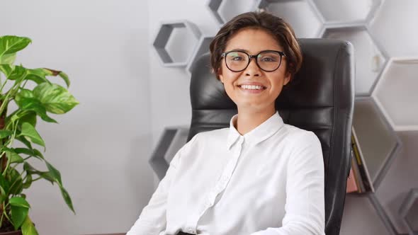 Beautiful Businesswoman Smiling Showing Okay Sitting in Armchair Slow Motion