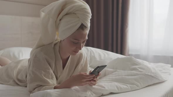 Young Woman Texting on Smartphone in Bed