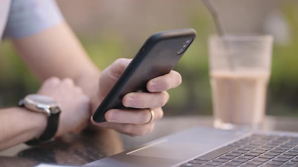 Closeup a Man with a Mobile Phone is Engaged in Online Banking Buys on the Internet and Writes