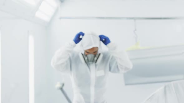 Mixed race male car mechanic putting protective clothes on and looking at the camera