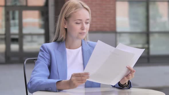 Young Businesswoman Reading Documents While Sitting Outdoor