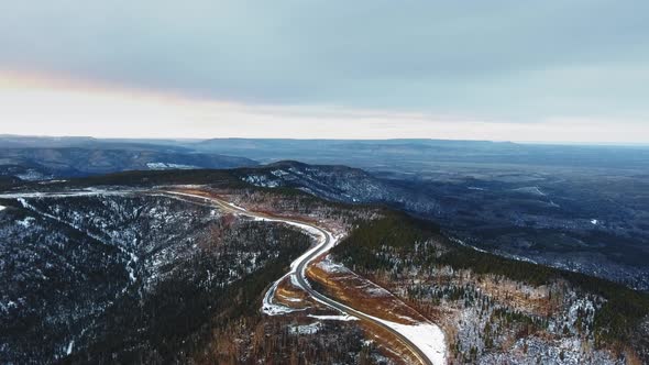 Aerial footage of car driving along the road, top of a mountain covered with snow in Alberta, Canada